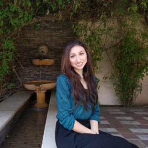 CURL Fellowship winner Aruna Dutt smiles while sitting in front of an outdoor fountain.