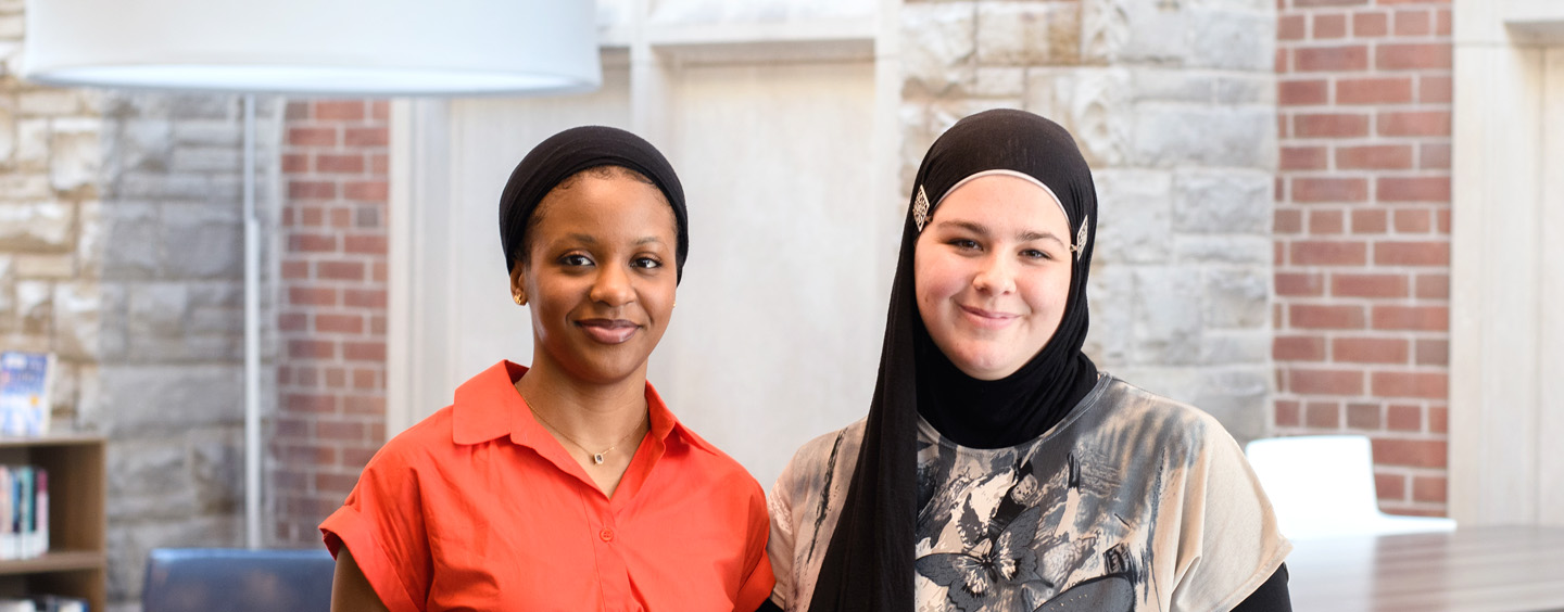 Faiza_and_Emilee_2025_cropped Faiza Gebi and Emilee Dagg standing side by side in Huron Library