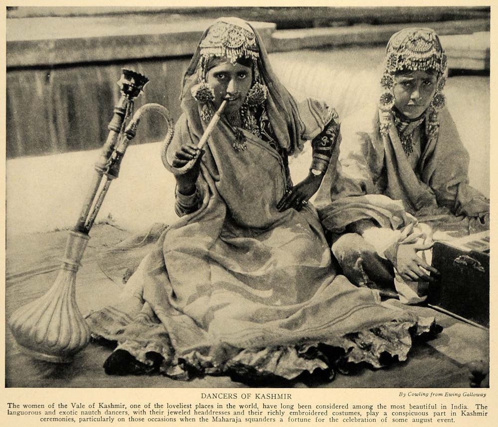 A photograph of two young dancing girls. The image caption reads: "The women of the Vale of Kashmir, one of the loveliest places in the world, have long been considered among the most beautiful in India. The languorous and exotic nautch dancers, with their jeweled headdresses and their richly embroidered costumes, play a conspicuous part in Kashmir ceremonies, particularly on those occasions when the Maharaja squanders a fortune for the celebration of some august event."
