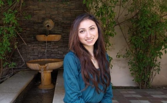 CURL Fellowship winner Aruna Dutt smiles while sitting in front of an outdoor fountain.