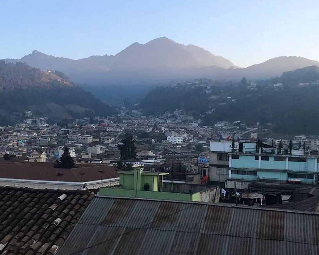 A landscape photo of the tops of houses in Guatemala. Foggy mountains are in the background.