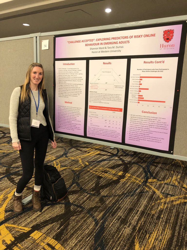 CURL Travel Bursary winner Shannon Ward smiles next to her poster at the SSEA conference in Toronto, Ontario. Her poster is entitled "Challenge Accepted: Exploring Predictors of Risky Online Behaviours in Emerging Adults." Shannon has long, blonde hair and wears a tan sweater and black leggings.