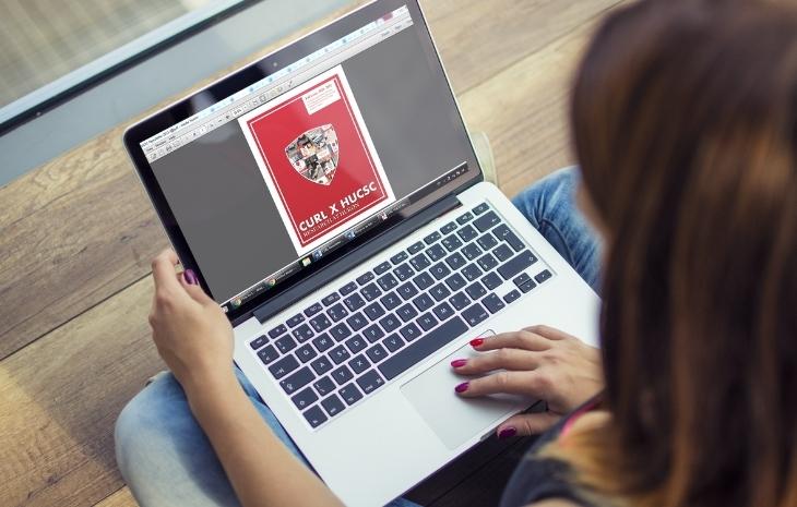 A photo of a student using their laptop. On the screen is the cover page of the Fall 2021-22 edition of the CURL x HUCSC newsletter.