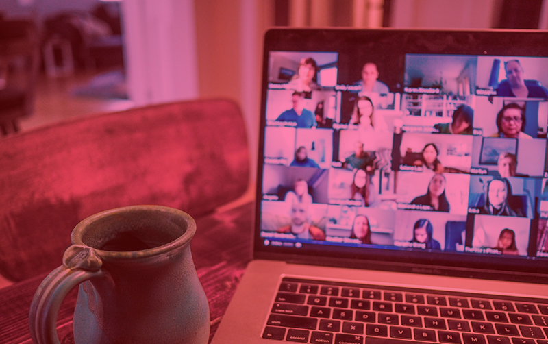 A photograph of a coffee mug next to a laptop showing a video conference.